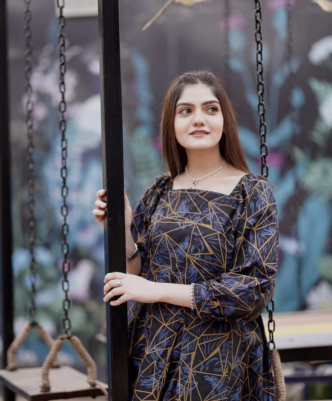 Model wearing a lotus print pure cotton midi gown on a swing, showcasing summer fashion and elegance.